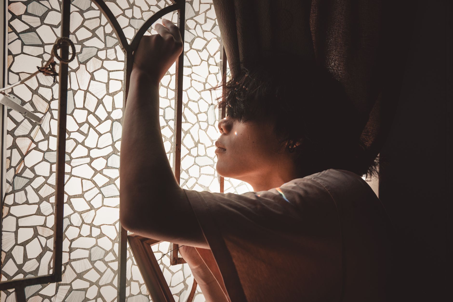 Eine Person öffnet ein Fenster und sieht ins Licht hinaus.